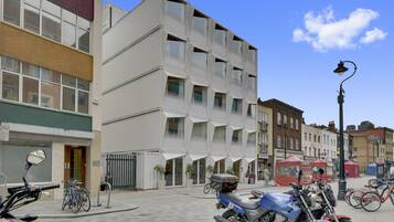 Un edifici modern amb una façana geomètrica original, una moto aparcada al davant i bicicletes a prop.