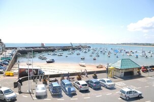 Un puerto con barcos, un muelle y un pequeño edificio con techo verde.