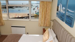 A hotel room with a large window offering a view of boats and a beach. - The Dolphin Hotel (St. Martin)