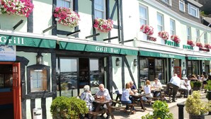 A traditional building with a 'Grill Bar' and 'Dolphin Hotel' signs, featuring outdoor seating and flower boxes. - The Dolphin Hotel (St. Martin)