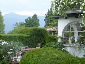 Um jardim exuberante com um edifício branco com uma grande janela em arco.