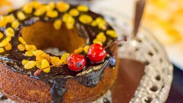 Un donut glaseado de chocolate con fruta seca y cerezas sobre un plato decorativo.