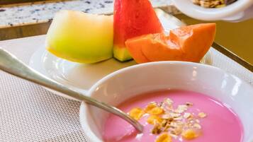 Une assiette de tranches de melon et un bol de yaourt rose agrémenté de granola.
