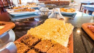 Una mesa de buffet con diferentes opciones de comida, incluyendo brownies y un plato con cobertura desmenuzable.