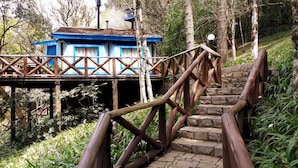 A wooden staircase leading to a blue building with a balcony, surrounded by greenery. - Villa Flor Ecoresort (Nova Petropolis)