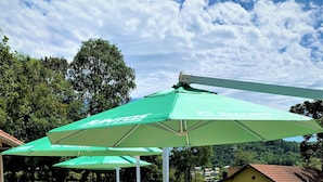 Outdoor seating with green umbrellas, wooden tables, and chairs. - Villa Flor Ecoresort (Nova Petropolis)