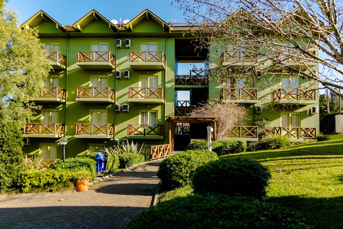A multi-story building with balconies, a pathway leading to the entrance, and well-maintained greenery.