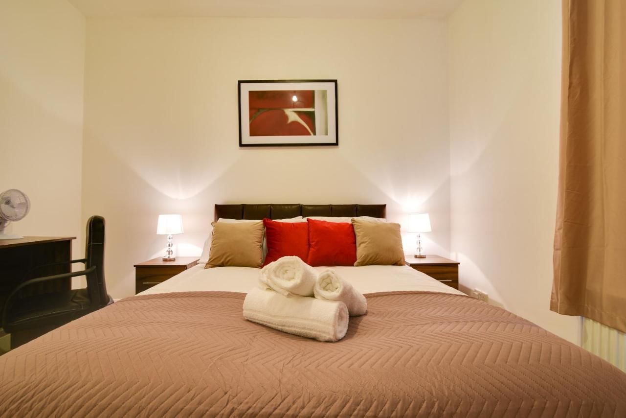 A hotel room with a large bed, two bedside tables with lamps, a chair, and a framed picture on the wall.