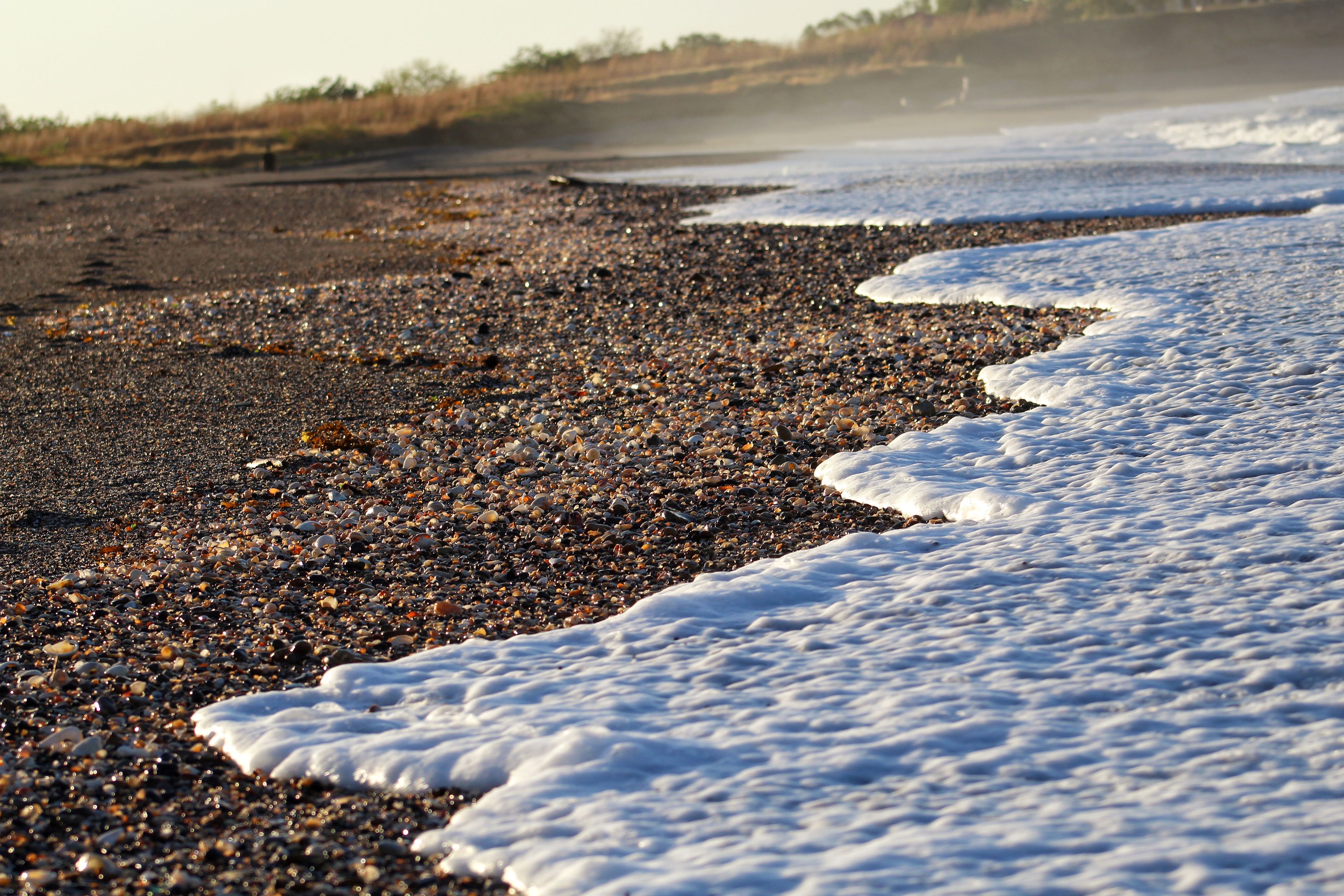 A pebbled beach with waves lapping at the shore.