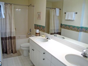 A bathroom with a bathtub, toilet, and a large vanity with two sinks. - Leeward Key Condos by Crystal Waters (Destin)
