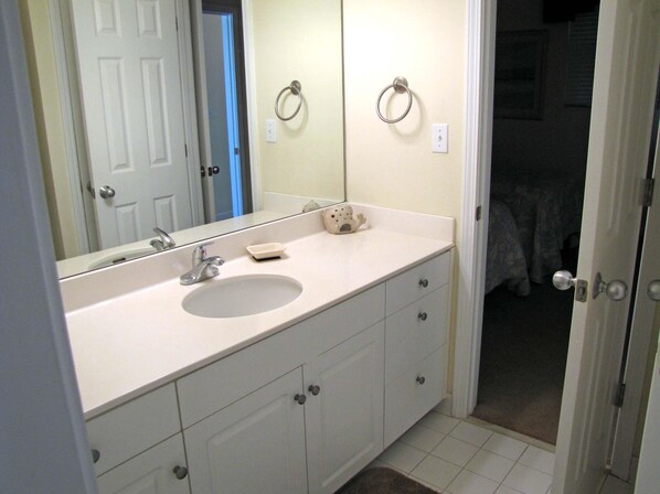 A bathroom with a white sink, mirror, and cabinets. - Leeward Key Condos by Crystal Waters (Destin)
