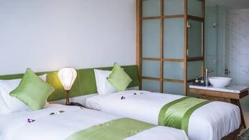 A hotel room with two beds, a wooden cabinet, a bathroom with a marble wall, and a green headboard.