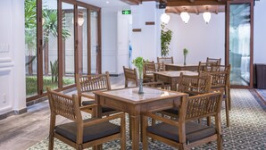 Een eetruimte met houten tafels en stoelen, grote ramen en een vloer met patroon.
