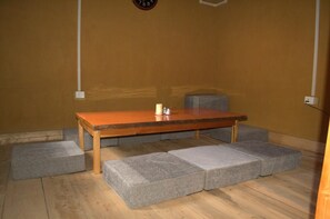 Une pièce avec une table en bois, des sièges rembourrés de couleur grise et une horloge murale.