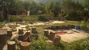 A rustic outdoor setting with a dirt path, wooden stumps, and potted plants. - AMA's Village Lodge (Paro)