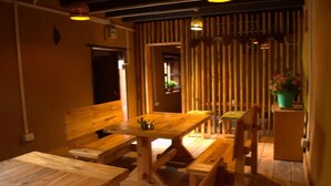 A wooden dining area with benches and a table, featuring a vertical bamboo screen in the background. - AMA's Village Lodge (Paro)