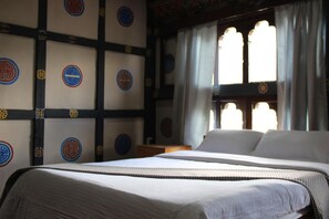 Une chambre avec un grand lit, une fenêtre avec des rideaux et un mur orné de motifs circulaires.