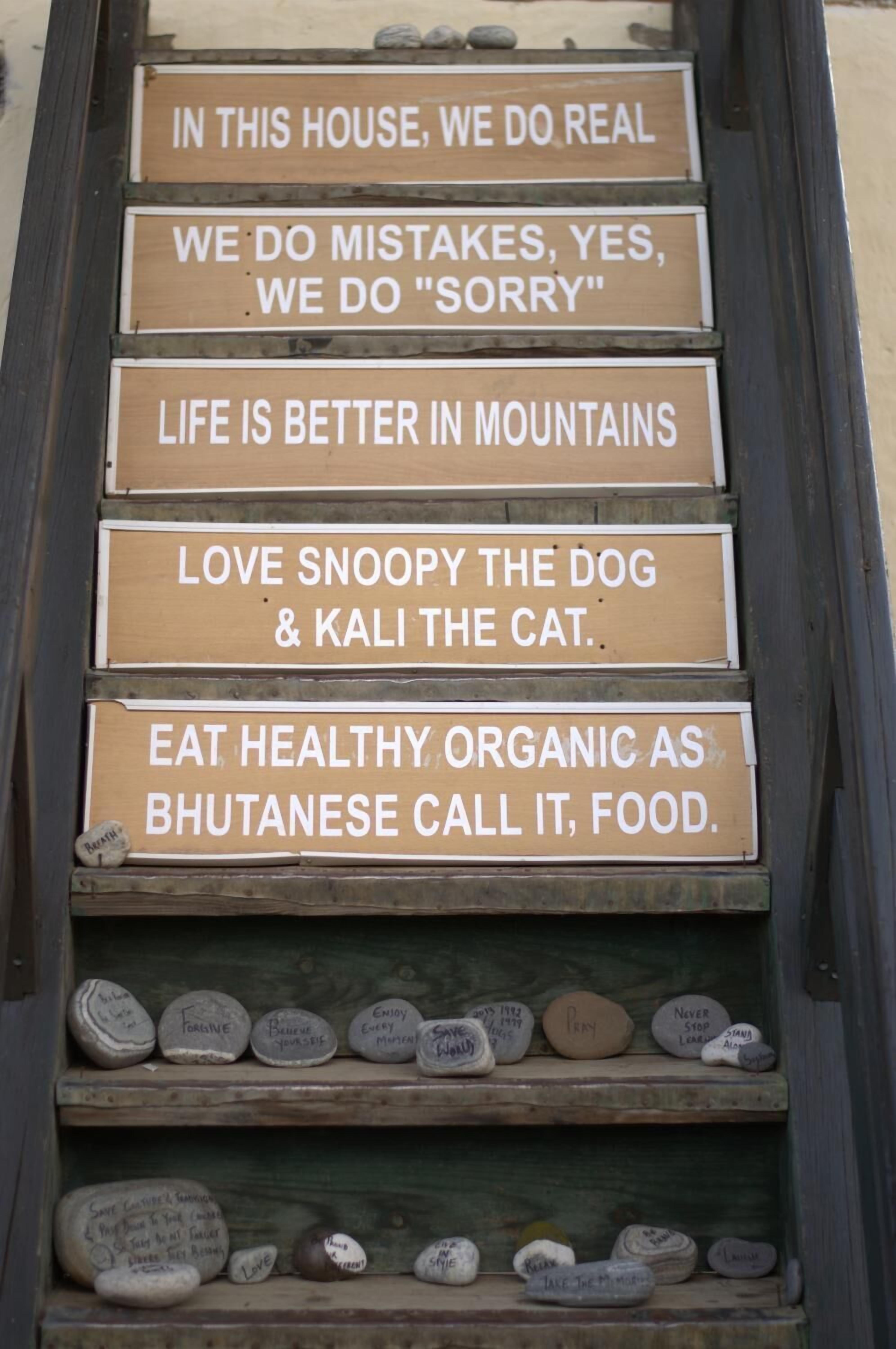 A wooden sign with motivational phrases and a shelf below with engraved stones.