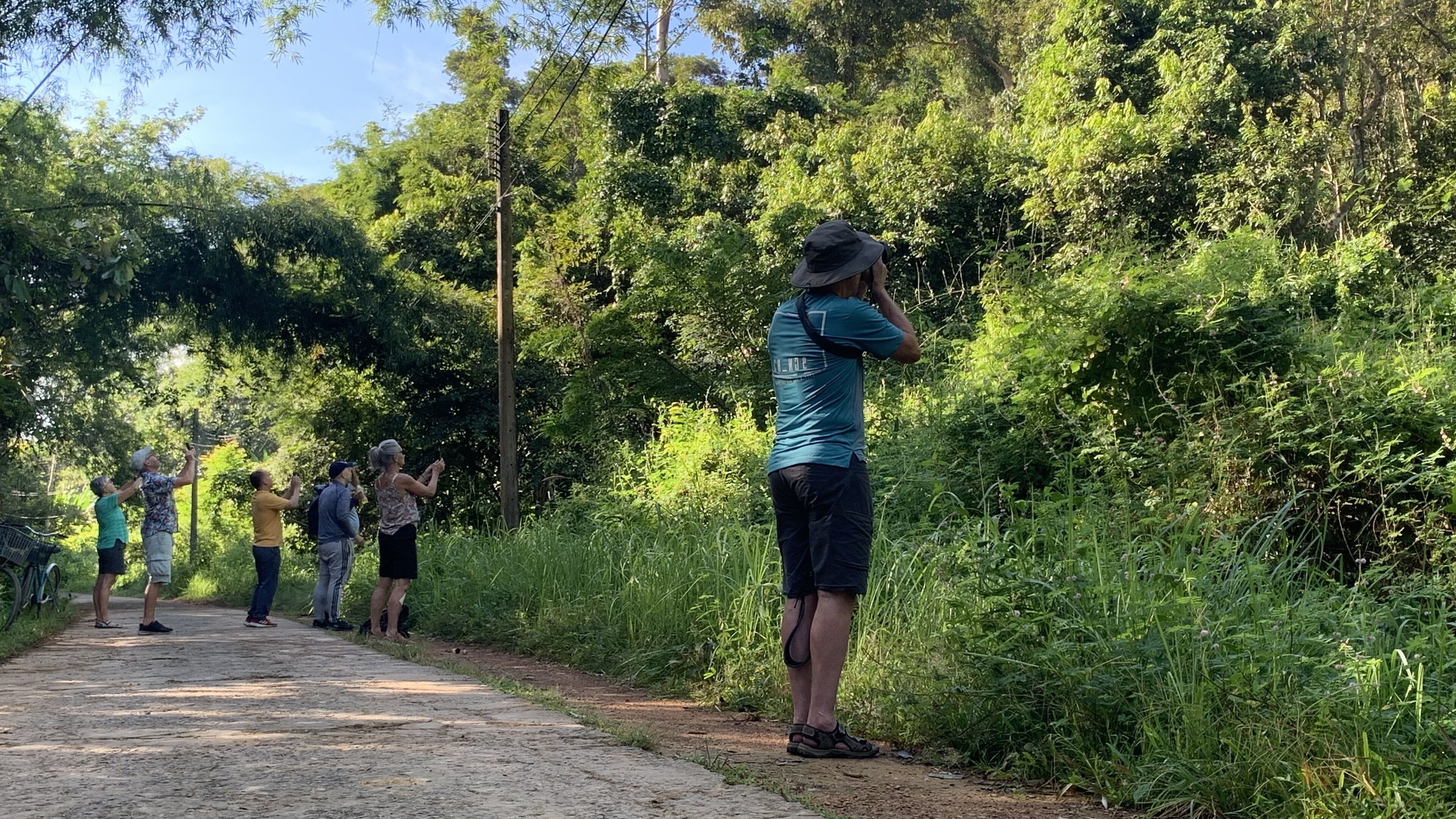 A group of people standing on a dirt path surrounded by dense greenery.