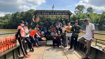 Um grupo de pessoas em um barco, com uma placa com a inscrição "AN TOAN LA TRÊN HỆT" ao fundo.