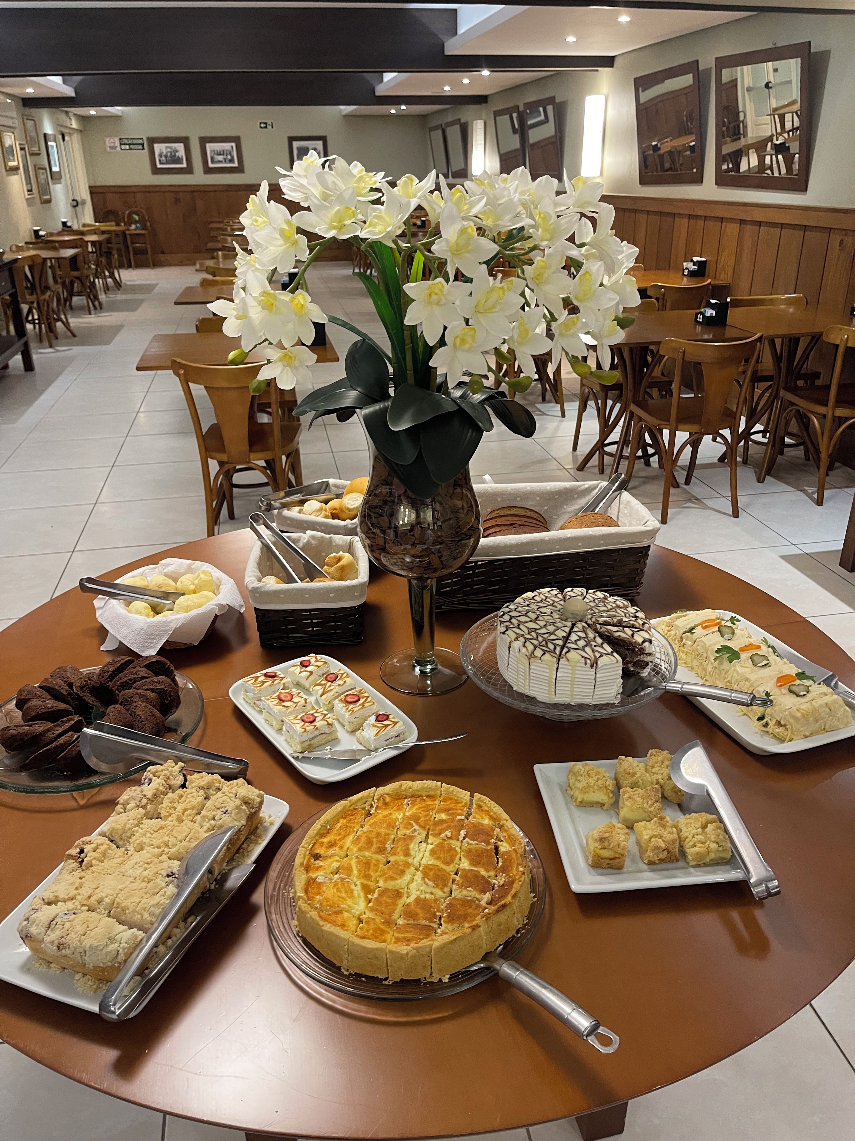Een buffet met diverse desserts en een vaas witte bloemen.