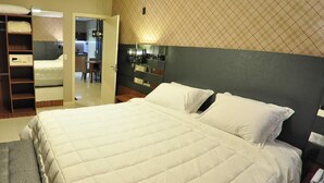 Una habitación de hotel con una cama grande, un armario y una pequeña kitchenette.