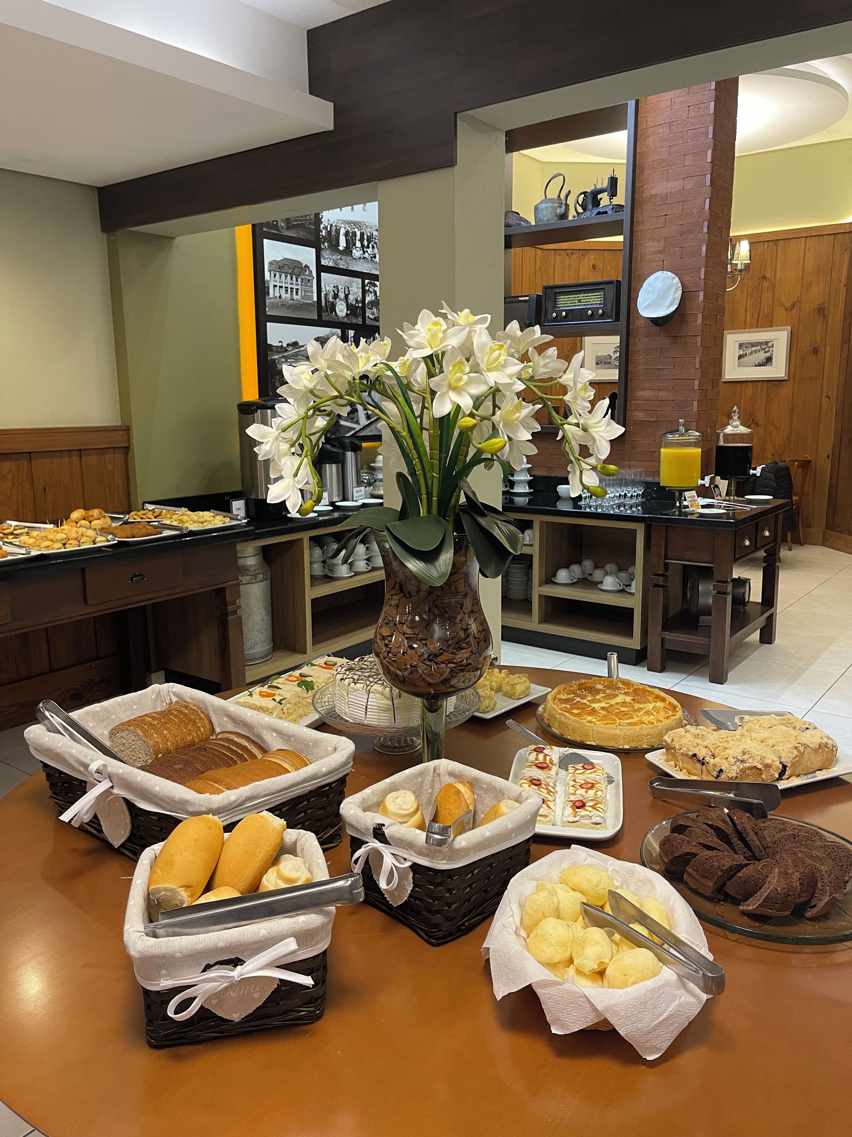 Une table de buffet garnie de divers plats, un vase rempli de fleurs blanches et une machine à café.