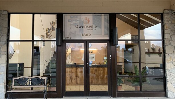 The entrance to Owensville Motor Inn with a wooden bench outside. - Owensville Motor Inn (Owensville)
