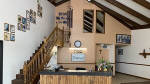 A reception area with a wooden counter, a staircase, and various framed pictures on the walls. - Owensville Motor Inn (Owensville)