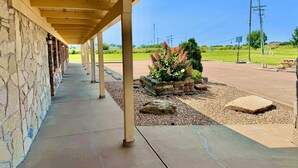 A covered outdoor area with a stone wall, a concrete pathway, and a planter with plants. - Owensville Motor Inn (Owensville)