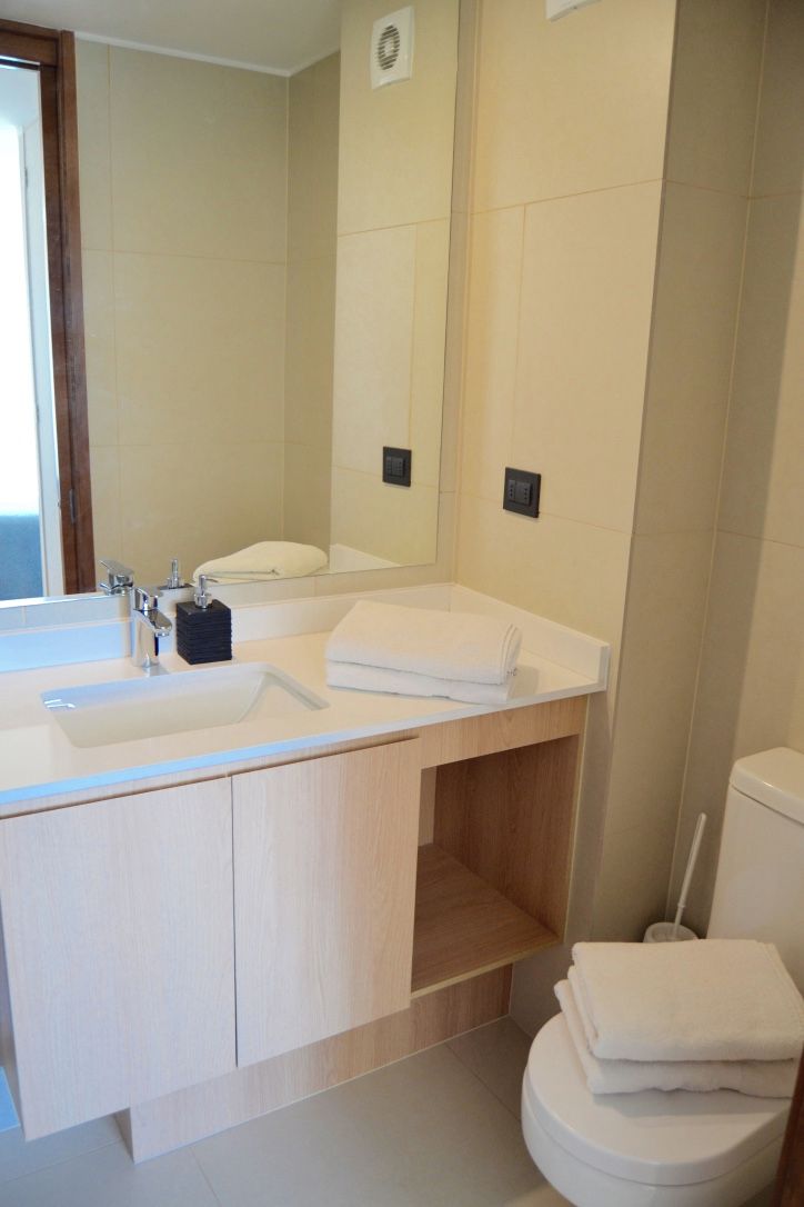A modern bathroom with a double sink, a mirror, and a toilet.