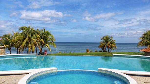 A swimming pool with a view of the ocean and palm trees. - Suite Rivas 126 Gran Pacifica Resort (Villa El Carmen)