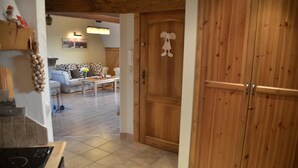 A wooden door with a cartoon character, a kitchen area with a stove, and a living room with a sofa and a table. - Apartament Gorski z Panorama Tatr (Bialy Dunajec)