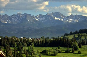 A mountainous landscape with a village in the foreground and snow-capped peaks in the background.