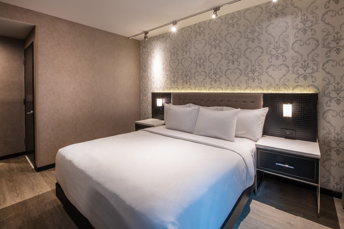Una camera d'albergo moderna con un letto grande, un comodino e una lampada a parete.