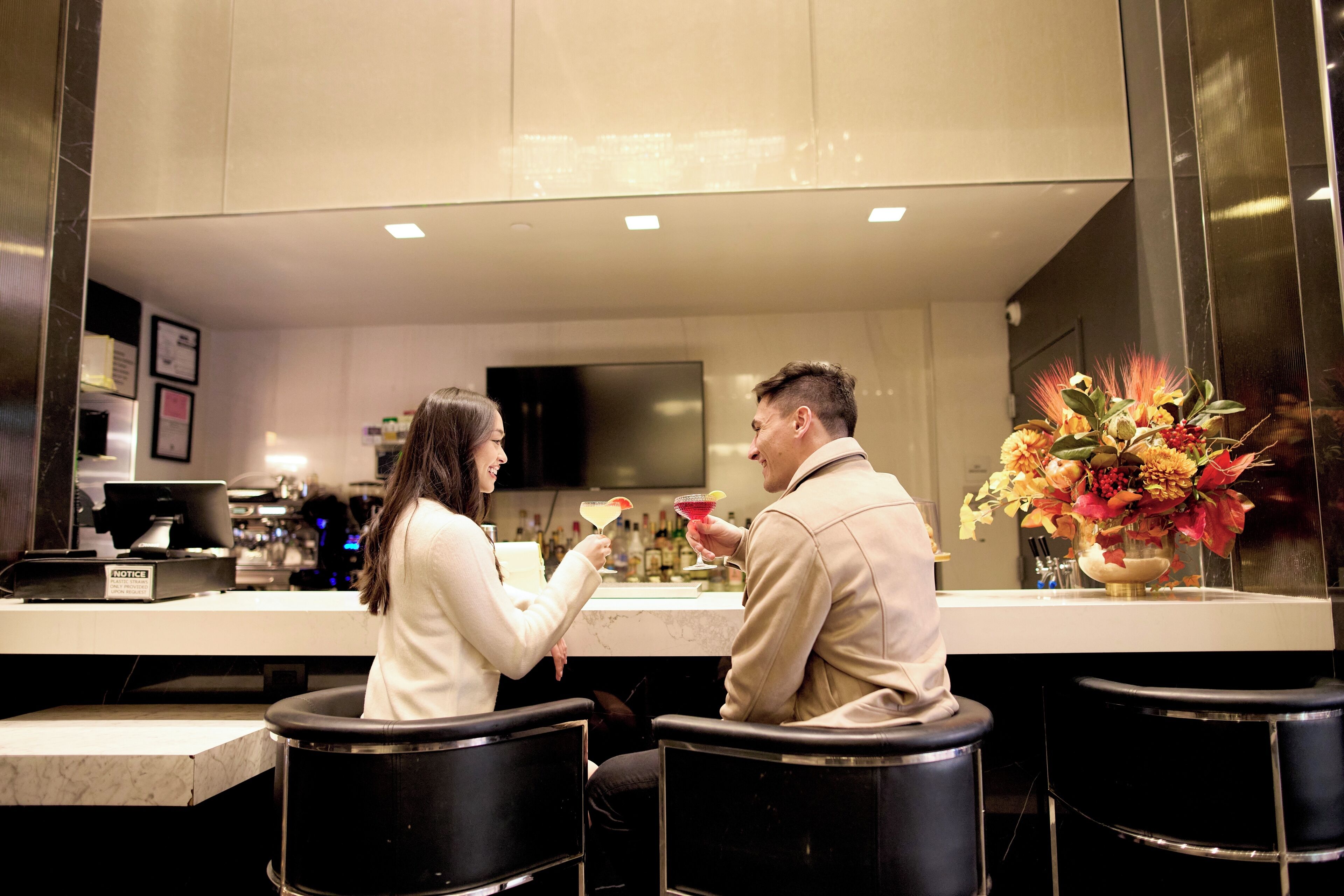 A modern bar area with a counter, bar stools, and a decorative vase with flowers.