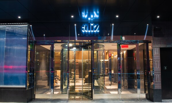 A modern hotel entrance with a revolving door and a glass facade. - Aliz Hotel Times Square (New York)