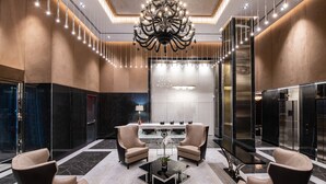 A modern lobby with a chandelier, seating area, and a reception desk. - Aliz Hotel Times Square (New York)