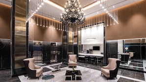 A modern lobby with a chandelier, seating area, and a bar.