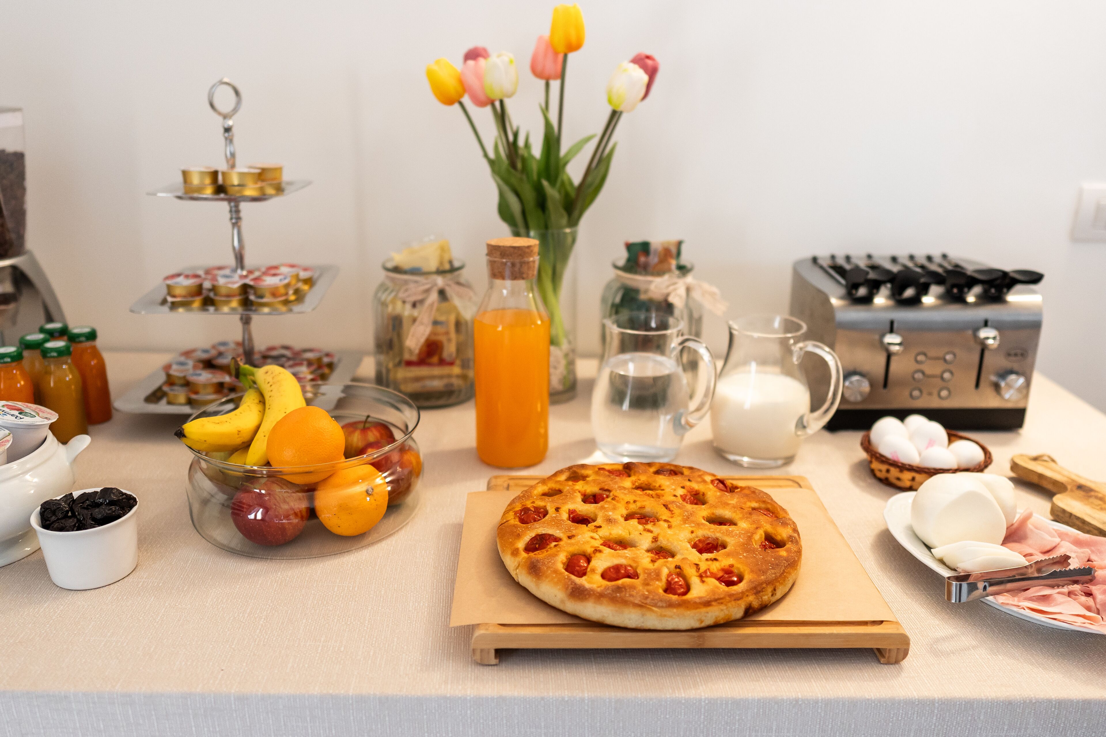 Une table de petit-déjeuner avec une variété d’aliments, notamment une pizza, des fruits, des œufs et des condiments.