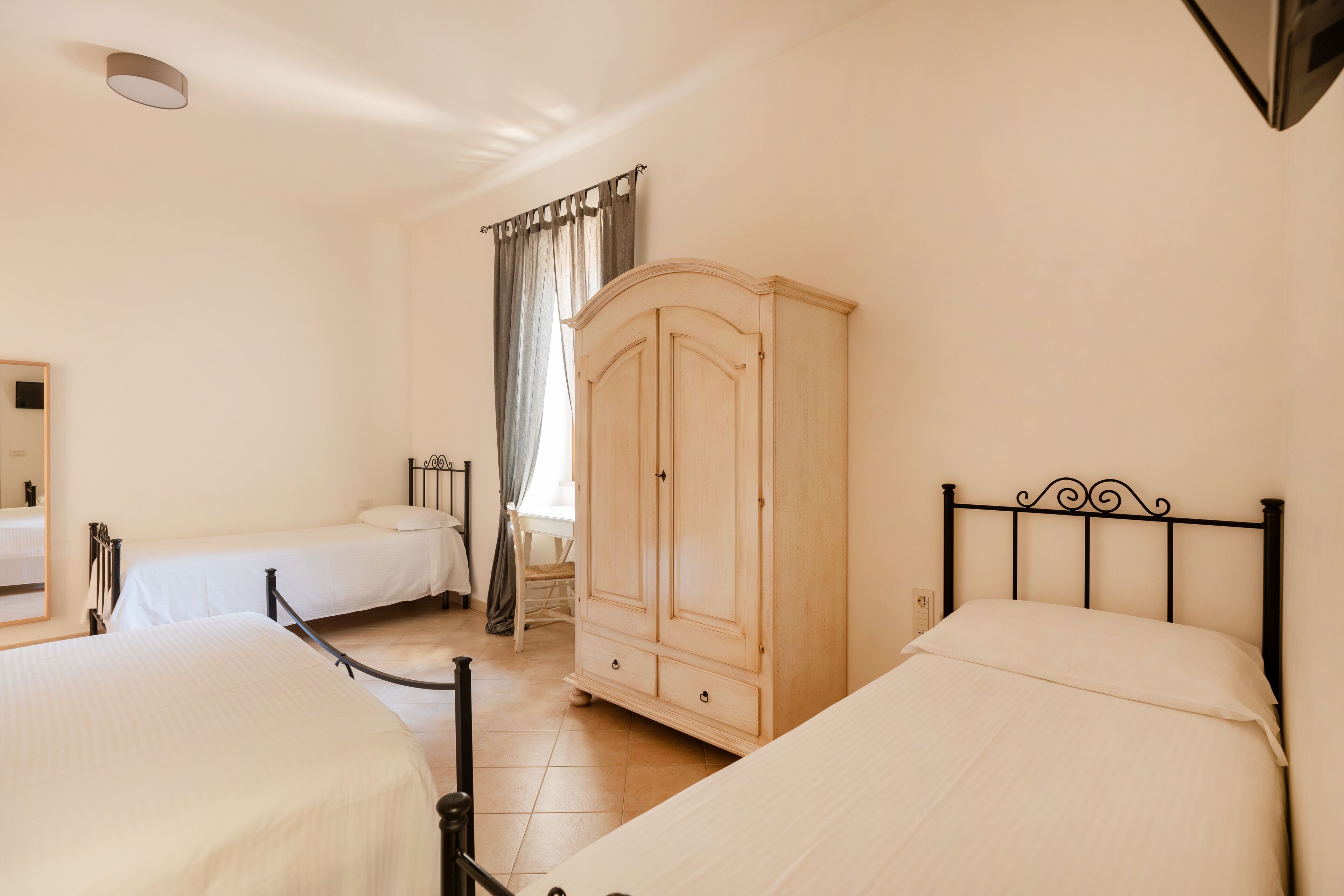 Un dormitorio con dos camas, un armario y una ventana con cortinas.