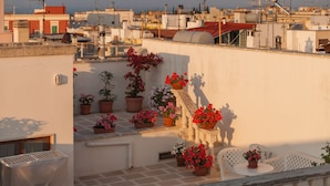 A rooftop terrace with potted plants and a small table. - Palazzo de Luca (Fasano)