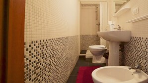 A bathroom with white tiled walls, a sink, a toilet, and a shower. - Gallipolis Terra (Gallipoli)