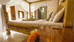 Un lit à baldaquin à quatre poteaux, doté d’une tête de lit en bois, d’une table de chevet et d’un miroir au mur.