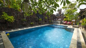 Une piscine rectangulaire à l’eau d’un bleu limpide, entourée d’un mur de pierre agrémenté de plantes.