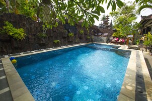 Una piscina al aire libre, sombrillas, sillones reclinables de piscina