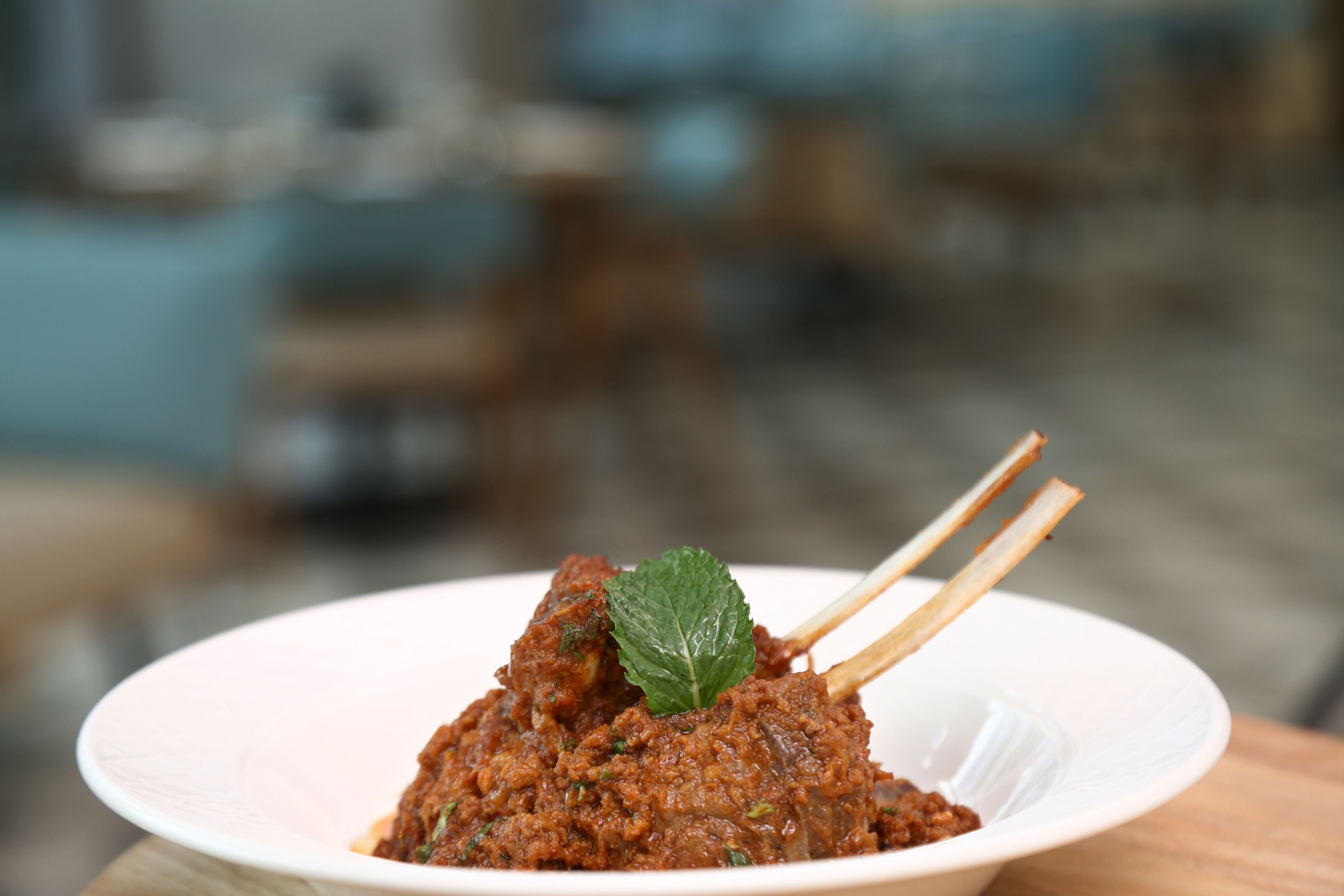 A bowl of food with a mint leaf garnish and chopsticks.