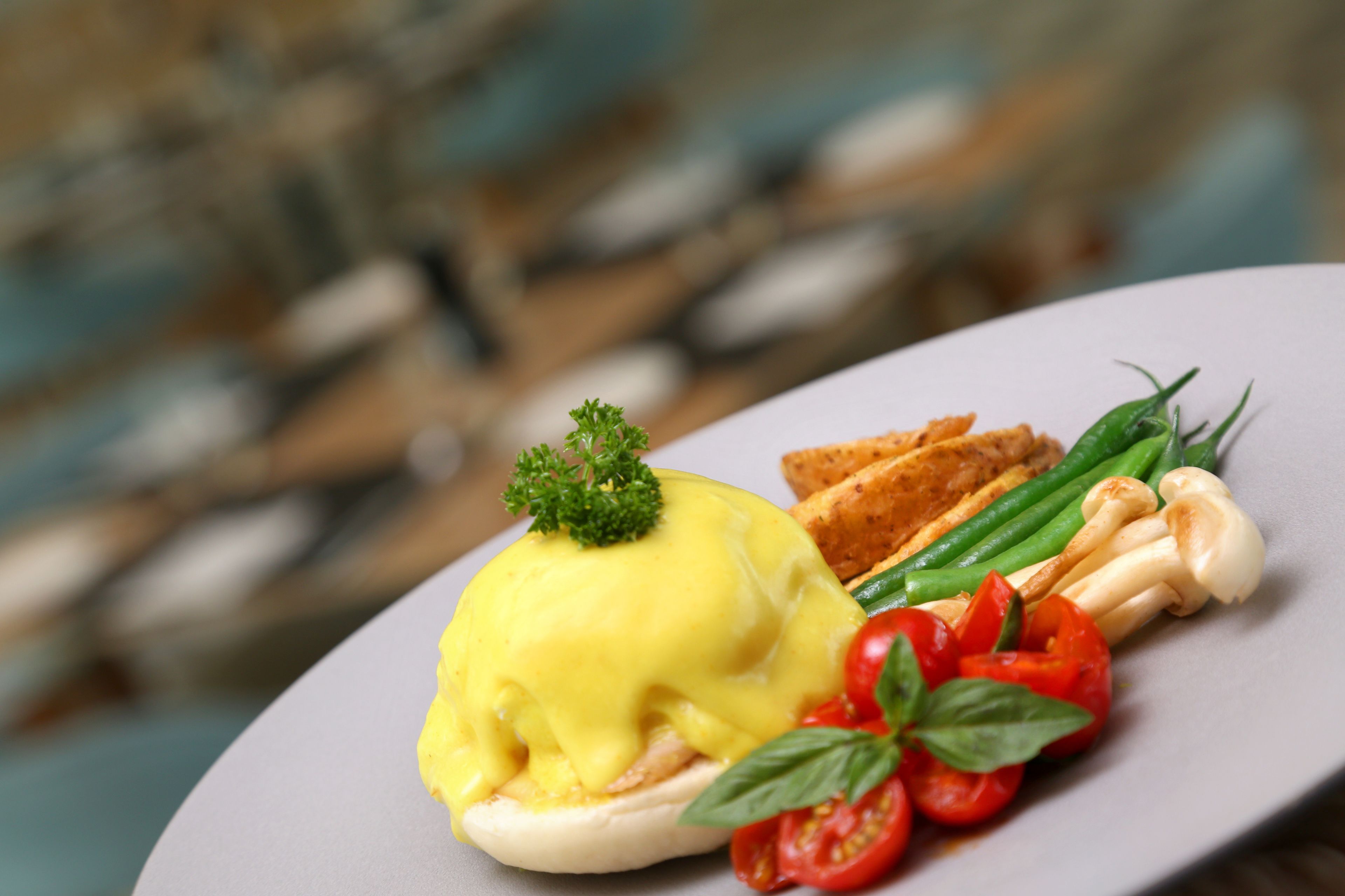 A plate with eggs benedict, green beans, cherry tomatoes, and a garnish.