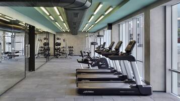 Ein Fitnessraum mit Laufbändern, Kraftgeräten und einer Spiegelwand.