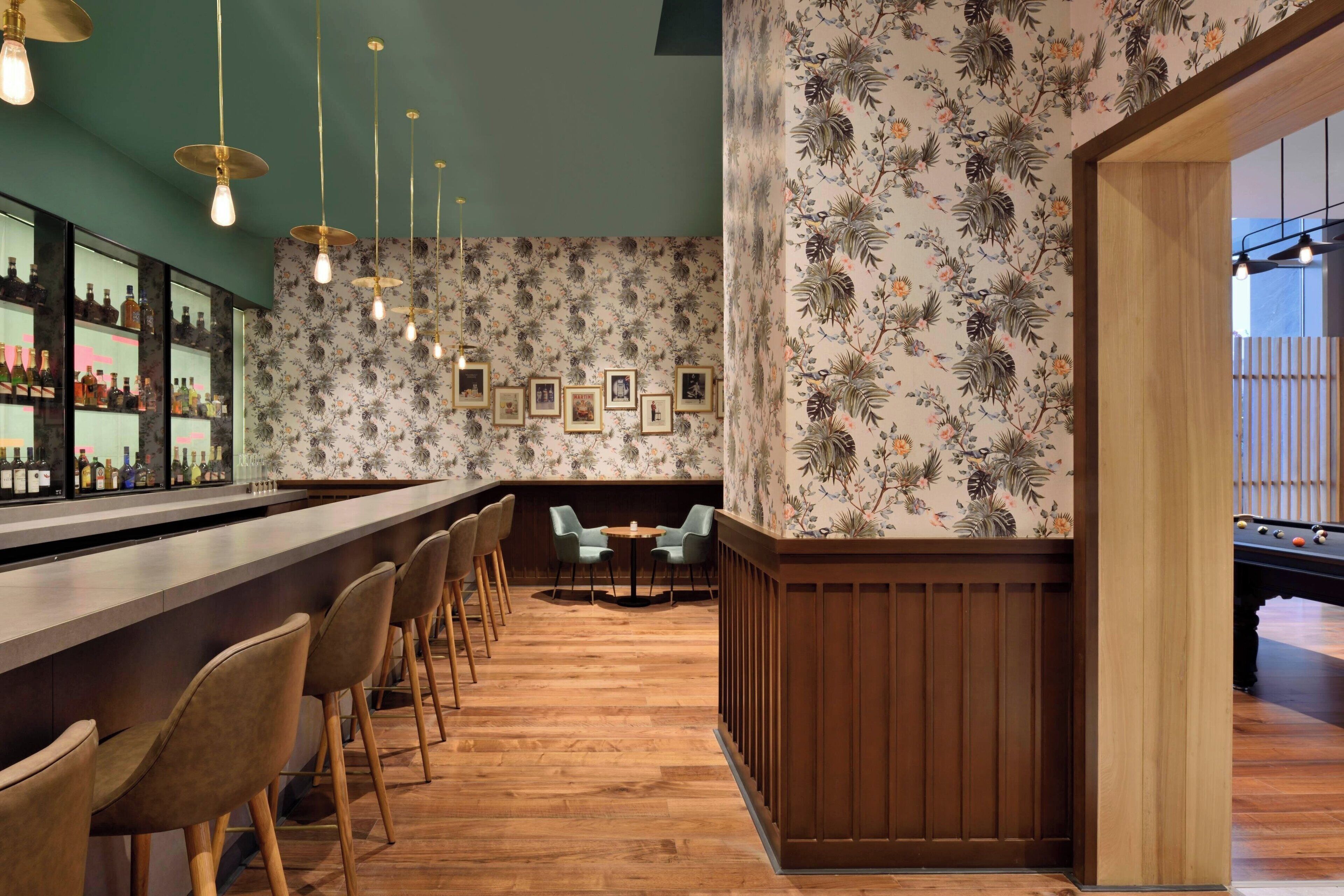 Un espace bar doté d’un plancher en bois, de tabourets et d’un mur orné de tableaux encadrés.